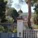 La residenza e il suo ampio giardino sono racchiusi da una lunga balaustra bianca e un raffinato cancello in parte dorato: quest'ultimo  incastrato tra due colonne sormontate da sculture consistenti in vasi di pietra colmi di pigne
